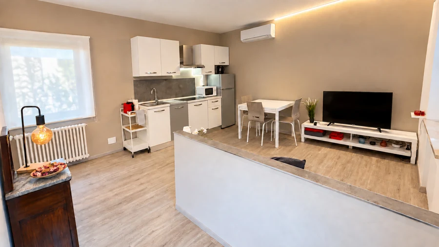 Cucina e soggiorno di Alkecè Red in un unico ambiente, con lampada a filamento e TV