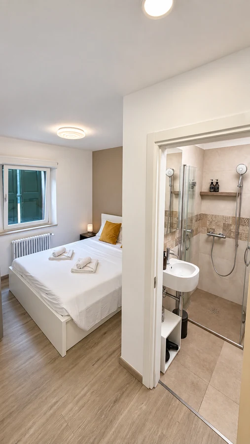 Vista sulla camera matrimoniale e sul bagno privato con doccia di Alkecè White